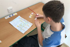 Chlapec ve výtvarce lepí ptáčky na výkres.