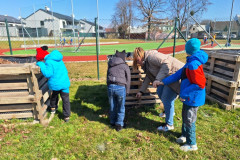 Žáci dávají staré listí do vyvýšeného záhonu.