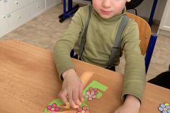 Chlapec dává papírové kytičky na papírový klíček.