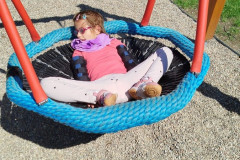 Dívka na dětském hřišti na houpačce.