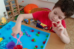 Chlapec trénuje jemnou motoriku a třídění barev.