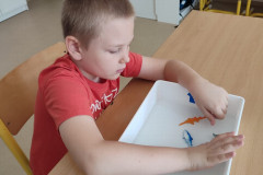 Chlapec si hraje s rybičkami v nádobě s vodou.