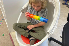 Chlapec v sedacím vajíčku s dřevěnou vkládačkou.