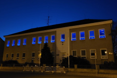 Budova školy nasvícená modře světýlky v oknech.