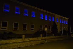Budova školy s modře podsvícenými okny.