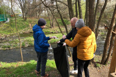 Žáci s panem asistentem dávají odpadky do pytle.