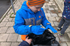 Chlapec dává odpadky do pytle.