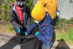 Žáci  dávají odpadky do pytle.