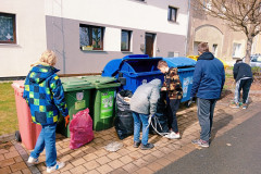 Žáci dávají odpadky do třídících kontejnerů.