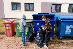 Žáci dávají odpadky do třídících kontejnerů.