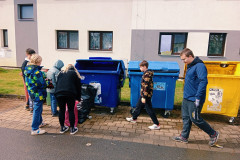 Žáci dávají odpadky do třídících kontejnerů.