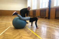 Chlapec v tělocvičně cvičí na gymballu.