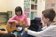 Dívka zkouší hrát na kytaru.