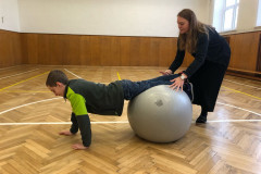 Chlapec v tělocvičně cvičí na gymballu.