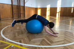 Chlapec v tělocvičně cvičí na gymballu.