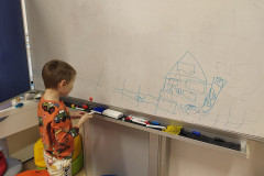 Chlapec maluje fixou na tabuli.