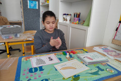 Dívka v lavici modeluje písmenka.