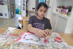 Dívka v lavici při výtvarce kreslí srdíčko.