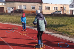 Žáci skáčí v kruzích na školním hřišti.