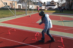 Chlapec skáče přes překážky na školním hřišti.