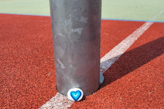 Namalovaný kamínek s modrým srdíčkem na školním hřišti.