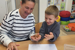 Chlapec s paní asistentkou obtiskávají ruku na papír.