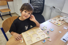 Chlapec v lavici pracuje se dřevěnou vkládačkou.